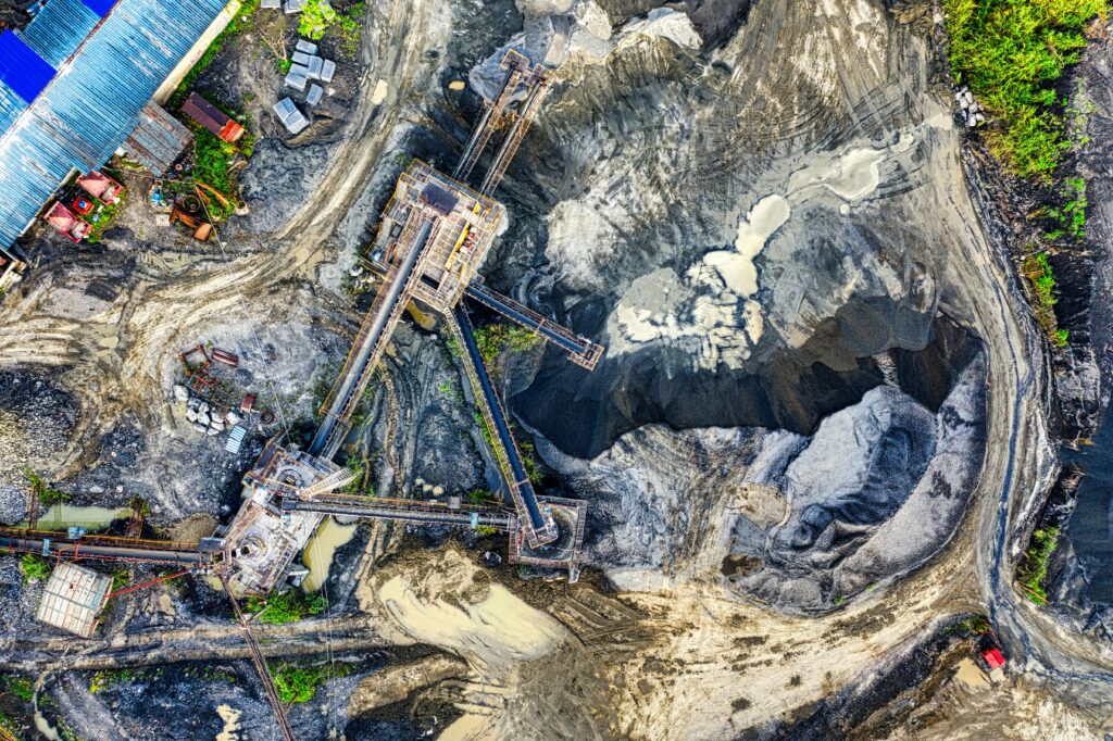 Top-down drone shot of an industrial mining site in Rumpin, West Java, showing machinery and excavation.